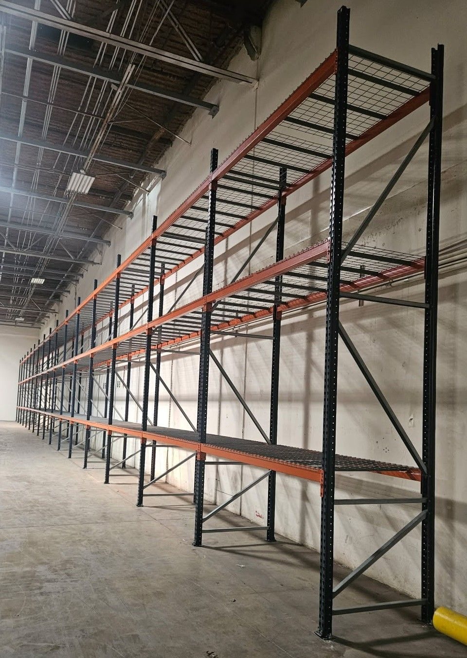 Wall line of selective pallet racking maximizing storage height under a high-pile permit